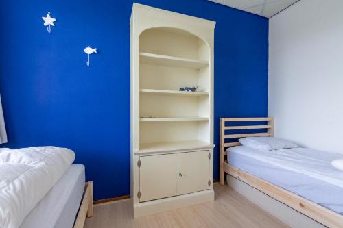 - une chambre avec un mur bleu et 2 lits dans l'établissement Strandslag 115 Beach Apartment, à Julianadorp