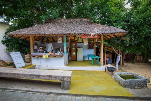 a small food stand with a large straw roof at My Village - Eco Rural Resort in Coimbatore