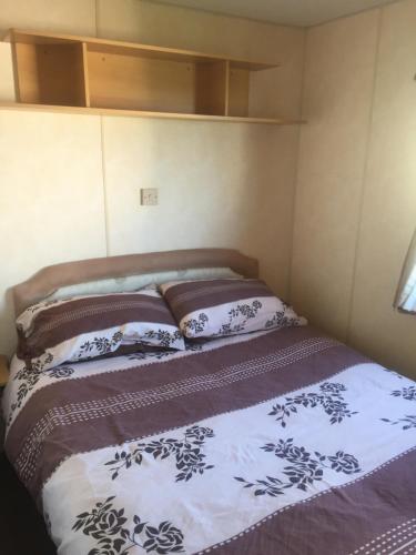 a bed in a room with two pillows on it at The 'Croyde' Caravan in Bideford