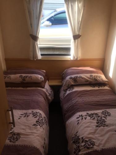 two beds in a small room with a window at The 'Croyde' Caravan in Bideford