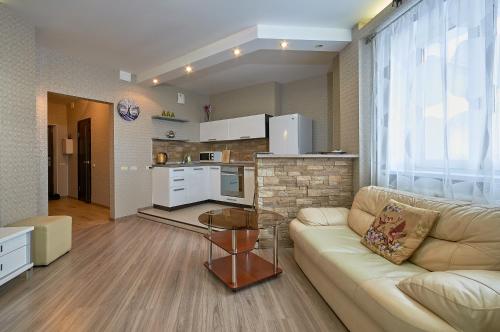 a living room with a couch and a kitchen at Ochag Apartments in Magnitogorsk