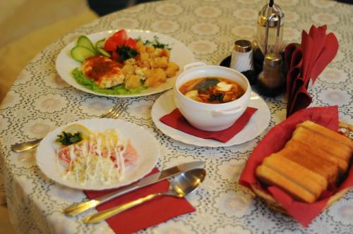 a table with plates of food and a bowl of soup at Patio MiniHotel in Tolyatti