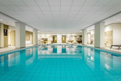 una gran piscina con suelo de baldosa azul en Fletcher Hotel-Restaurant Frerikshof en Winterswijk