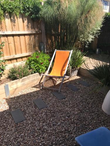 an orange chair sitting in the middle of a yard at Sunset Over Sea Little Beachside Villa Rosebud McCrae in Rosebud