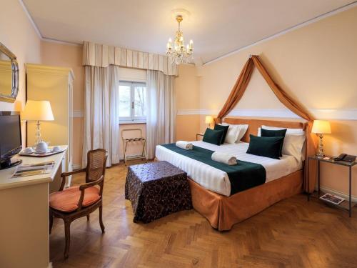 una camera d'albergo con un grande letto e una scrivania di Hotel Villa Carlotta a Firenze