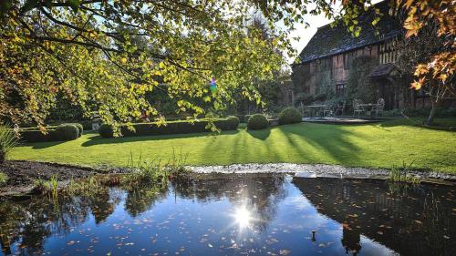 a house with a pond in the middle of a yard at Langshott Manor - Luxury Hotel Gatwick in Horley