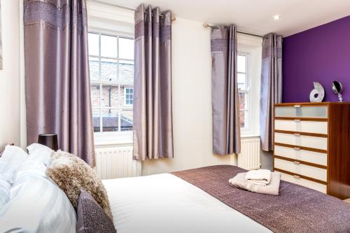 ヨークにあるCity Apartments - Buckingham Courtのベッドルーム1室(紫の壁のベッド1台、窓付)