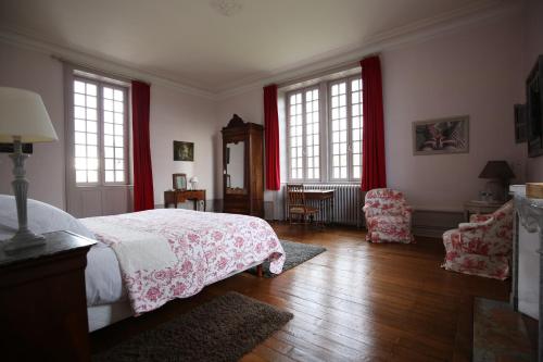 a bedroom with a bed and two windows with red curtains at La Sicorie in Saint-Germain-le-Guillaume