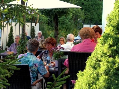 a group of people sitting at a table in a garden at Best Breakfast - Hotel Justina in Bad Wörishofen