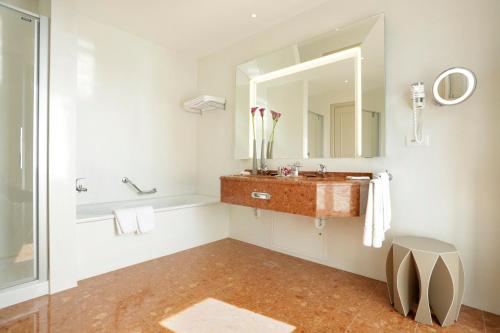 a bathroom with a toilet, sink, mirror and tub at Hotel Schweizerhof Luzern in Lucerne