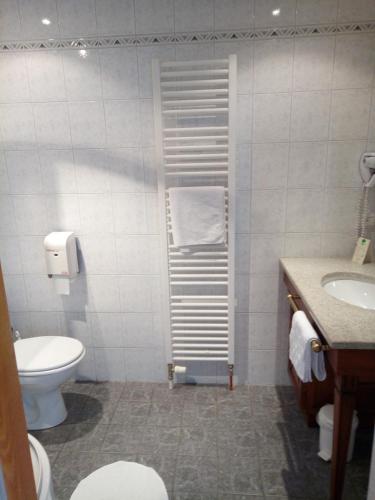a white bathroom with a toilet and a sink at Hôtel Restaurant Le Bristol in Niederbronn-les-Bains