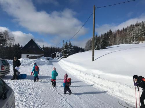 een groep mensen die over een besneeuwde weg lopen bij FeWo direkt am Loipeneinstieg Achtung derzeit Bauarbeiten am Gebäude in Johanngeorgenstadt