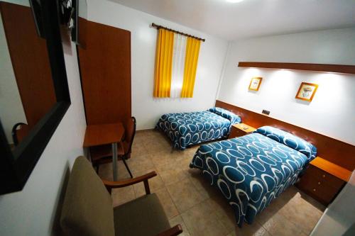 a hotel room with two beds and a table at Hostal Restaurante El Surtidor in Caspe