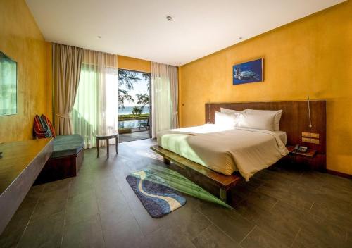 une chambre avec un grand lit et une grande fenêtre dans l'établissement Coriacea Beachfront Boutique Phuket Resort, à Mai Khao Beach