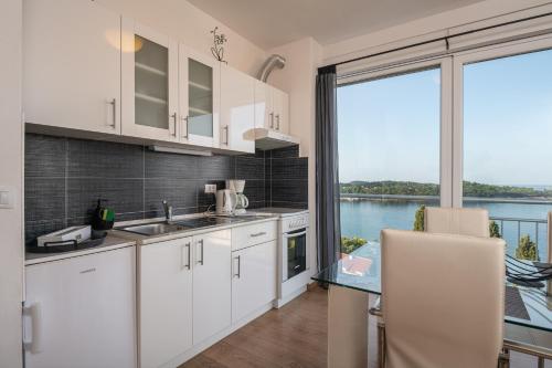 une cuisine avec des placards blancs et une vue sur l'eau dans l'établissement Apartments Didan, à Cavtat