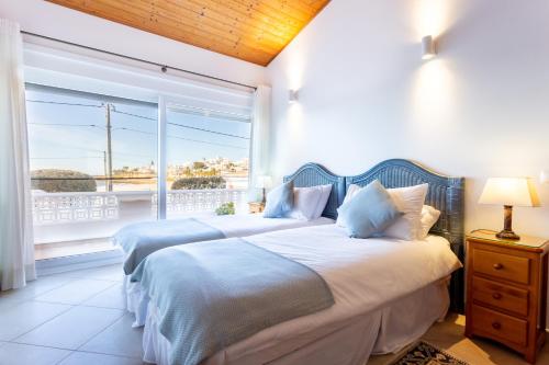um quarto com 2 camas e uma grande janela em Casa Bom Porto na Praia da Luz