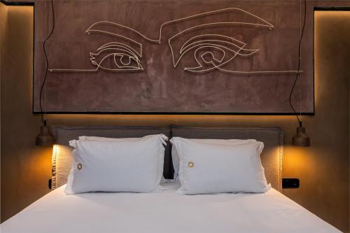 a bed with two white pillows and a painting on the wall at Onira Suite Dreams in Hersonissos