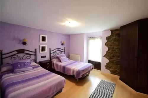 two beds in a bedroom with purple walls and a window at CASA TENA in Biescas