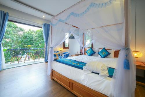 a bedroom with a canopy bed and a balcony at Hoi An Sea Village Homestay in Hoi An
