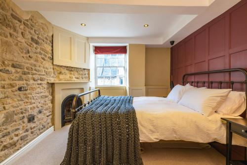 a bedroom with a bed and a brick wall at Number 6 Stamford - Boutique Grade II Listed Townhouse in Stamford