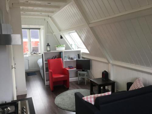 a living room with a red chair and a desk at B&B Alkmaars Toppunt in Alkmaar