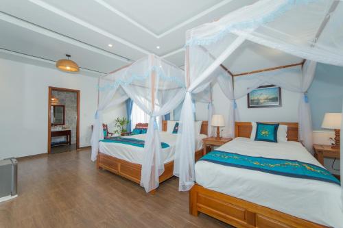a bedroom with two beds and a canopy bed at Hoi An Sea Village Homestay in Hoi An