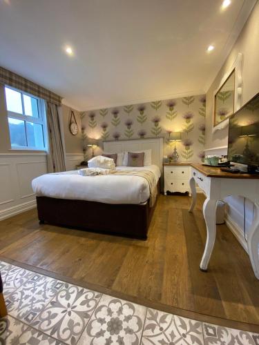 a bedroom with a bed and a desk with a television at The Inn At Grasmere in Grasmere