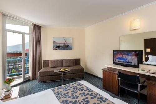 a hotel room with a couch and a television at Leonardo Club Tiberias - All Inclusive in Tiberias