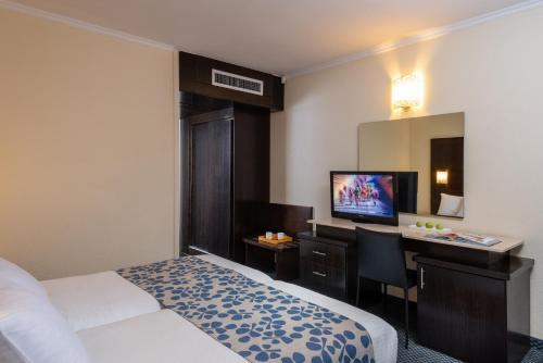a hotel room with a bed and a desk and a television at Leonardo Club Tiberias - All Inclusive in Tiberias