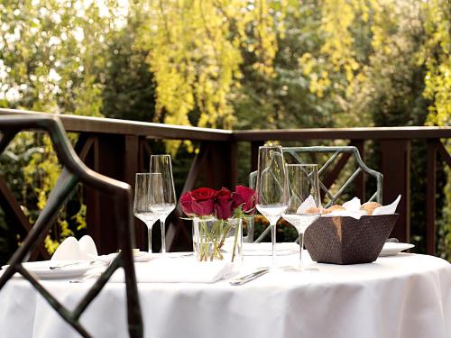 a table with wine glasses and red roses on it at Langshott Manor - Luxury Hotel Gatwick in Horley