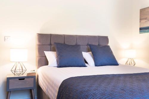 una camera da letto con un grande letto con cuscini blu di Blue Door Apartments a Newcastle