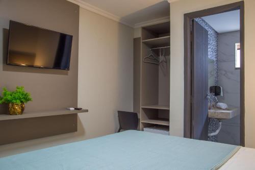 a bedroom with a bed and a tv on the wall at Juazeiro Comfort Hotel in Juazeiro do Norte