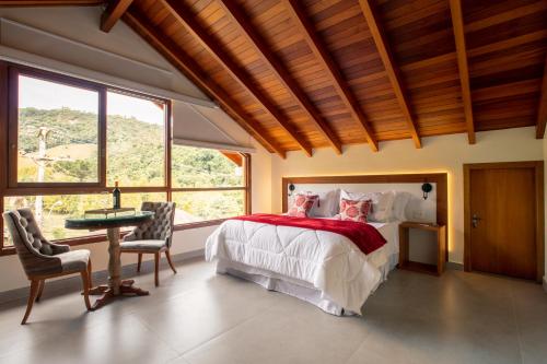 a bedroom with a bed and a table and chairs at Vinicola e Pousada Peculiare in Bento Gonçalves