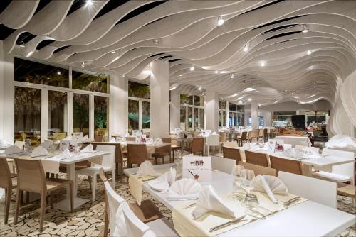 a restaurant with white tables and chairs and a ceiling at Hotel Baia Azzurra - Lake Front in Nago-Torbole