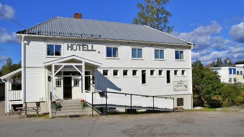 a white house with a black and white checkered roof at Hotell Magnor Bad in Magnor