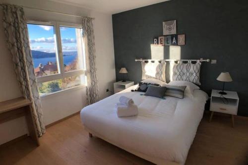 - une chambre avec un grand lit blanc et une grande fenêtre dans l'établissement ROC & LAC - Terrasse vue lac, piscine, parking, à Veyrier-du-Lac