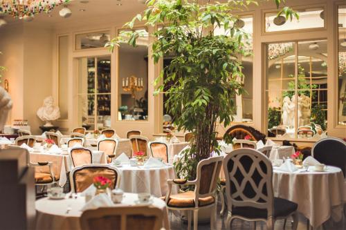 a restaurant with white tables and chairs and a plant at Grand Palace Hotel - Small Luxury Hotels of the World in Rīga
