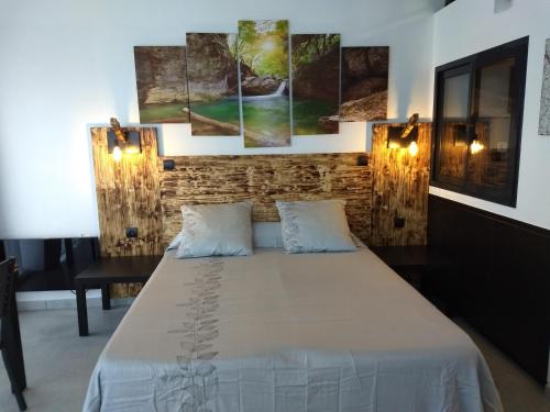 a bedroom with a bed and a wall with paintings at Les Terrasses de Valensole in Valensole