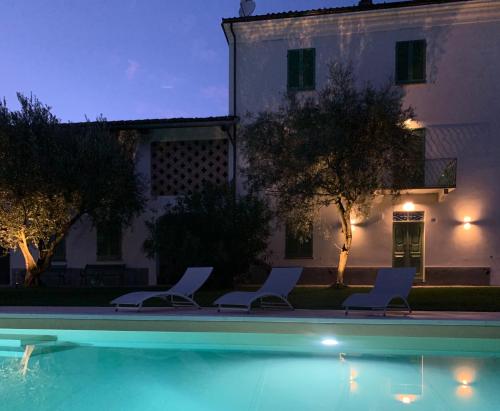 a swimming pool with two chairs and a house at Laficaia in Mombaruzzo