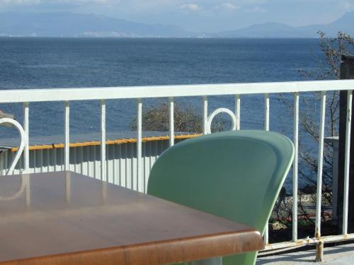 una mesa y una silla verde en un balcón con vistas al océano en Hotel Mudanya, en Mudanya