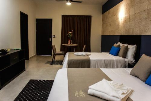 a hotel room with two beds and a table at Hotel Los Frailes, Valladolid, Yucatán in Valladolid