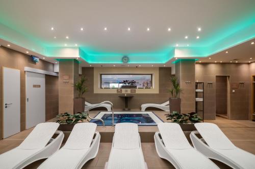 a conference room with a hot tub and white chairs at Bükkös Hotel & Spa in Szentendre
