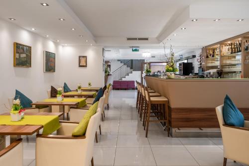 a restaurant with tables and chairs and a bar at Bükkös Hotel & Spa in Szentendre