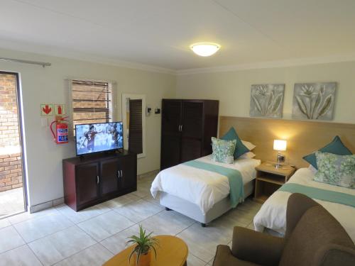 a hotel room with two beds and a flat screen tv at Sunbird Garden Cottage in Pretoria