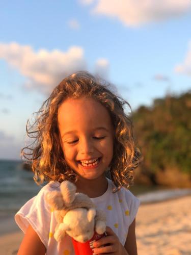 a little girl holding a teddy bear on the beach at YOISAMA Sunset Beach House in Ishigaki Island