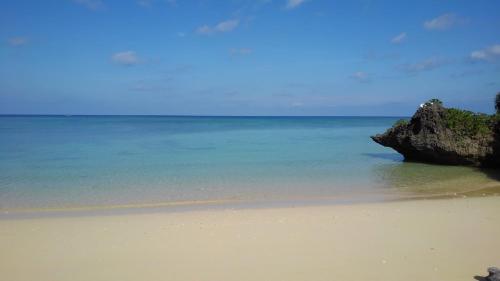 a sandy beach with a rock in the ocean at YOISAMA Sunset Beach House in Ishigaki Island