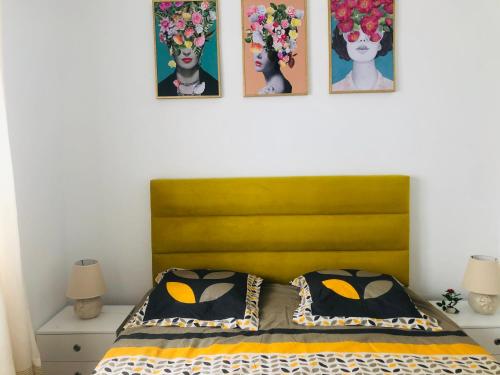 a bed with a yellow headboard and four pictures on the wall at The New luxury appart In la Marsa Beach in La Marsa