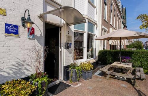 a building with an umbrella and a table and a bench at Hotel 't Witte Huys Scheveningen in Scheveningen