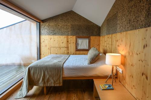 1 dormitorio con cama y ventana grande en Vale do Ninho Nature Houses, en Ferraria de São João