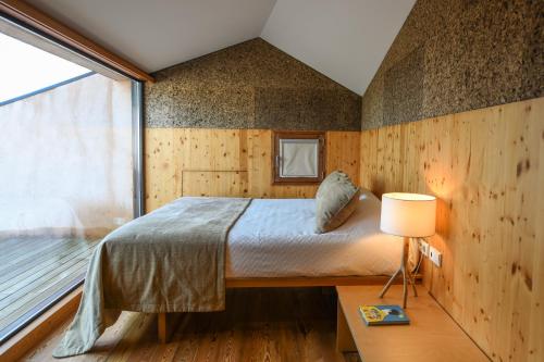 una camera da letto con un letto e una grande finestra di Vale do Ninho Nature Houses a Ferraria de São João